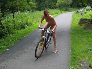 Dana riding a bike in the park naked